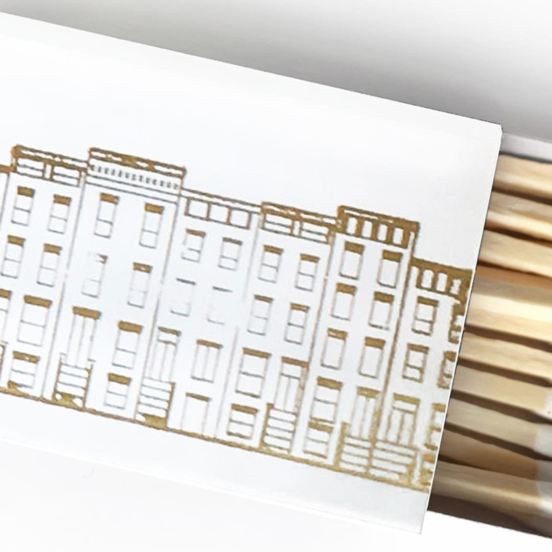 "Cozy Village Matchbox, Gold on White" - Matchbooks and Matches in gold by Jessica Cunningham