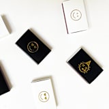 "Party Emoji Matchbox, Gold on Black" - Party Matches and Matchbooks in gold by Jessica Cunningham