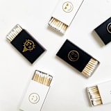 "Party Emoji Matchbox, Gold on Black" - Party Matches and Matchbooks in gold by Jessica Cunningham