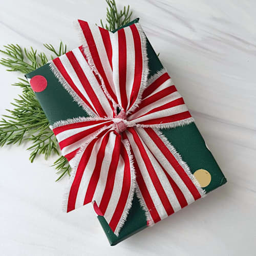 This is a red holiday decorations by Honey Silks Co called 2" cotton hand frayed striped holiday ribbon in standard