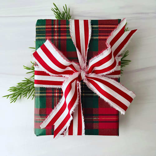 This is a red holiday decorations by Honey Silks Co called 1.5" hand frayed cotton stripe ribbon in standard