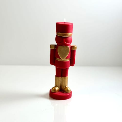 This is a multicolor candles and candle holders by Over By The Moon called red and gold nutcracker candle in standard