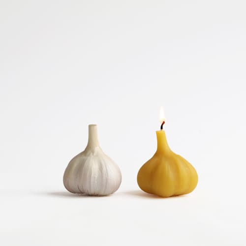 This is a yellow candles and candle holders by Artifaqt called garlic beeswax candles - 4 in standard