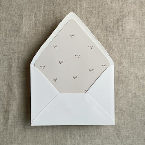 This is a beige wedding envelopes by Ivory Invitations called baby ribbon bows printed envelope liner for a7 euro flap envelope | pack of 10 in standard
