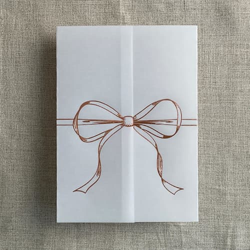 This is a pink vellum wedding invitations by Ivory Invitations called rose gold ribbon bow foil stamping vellum wrap for 5x7 card | pack of 10 in standard