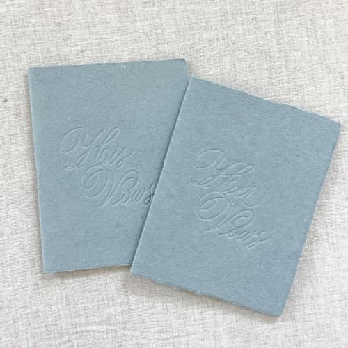 This is a blue vow books by Orchid Studio called debossed print vow books - set of 2 - dusty blue in standard