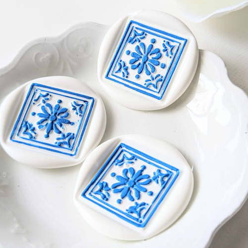 This is a white wax seals by Inkspiringletters called artisan tile- white and blue-set of 25 hand-crafted wax seals in standard