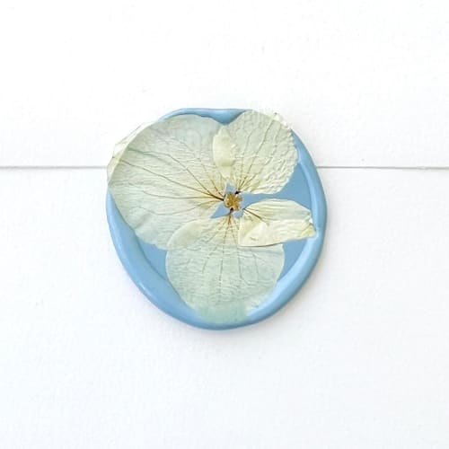 This is a blue wax seals by Caitlin Home called white hydrangea wax seal in dusty blue | pack of 10 in standard