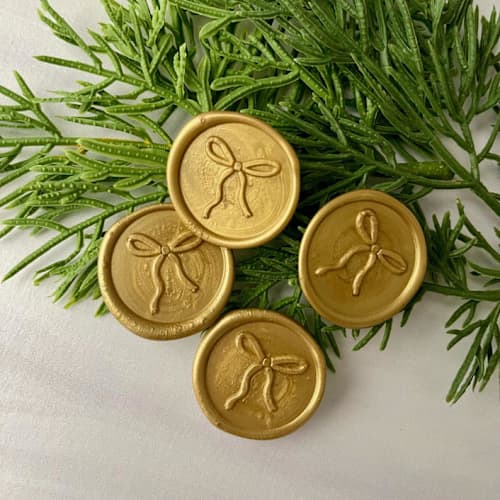 This is a gold wax seals by Honey Silks Co called bow gold wax seal - set of 10 in standard
