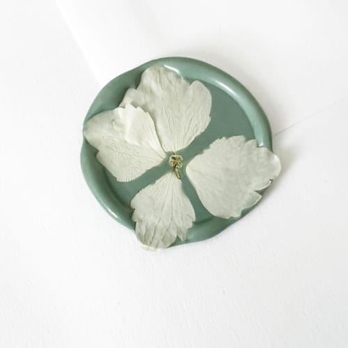 This is a green wax seals by Caitlin Home called white hydrangea in sage wax seal | pack of 10 in standard