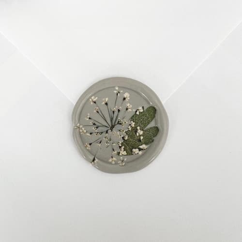 This is a gray wax seals by Caitlin Home called queen anne's lace and leaf in linen wax seals | pack of 10 in standard