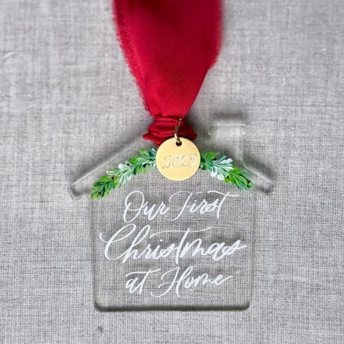This is a clear holiday decorations by Orchid Studio called first christmas at home - house shaped ornament in standard