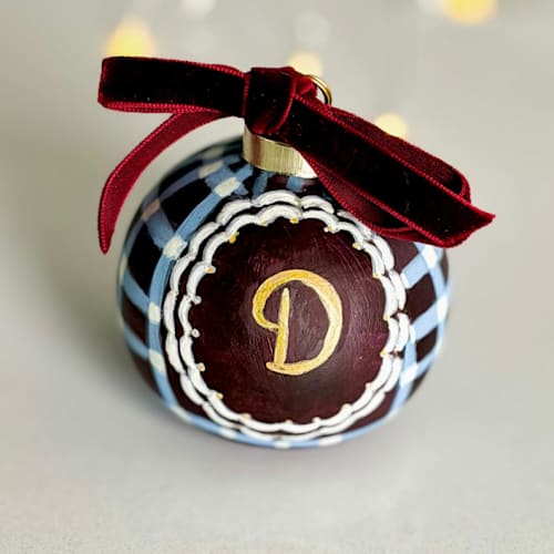 This is a brown holiday decorations by Arohika Verma called personalized hand-painted burgundy & blue plaid monogram ornament in standard