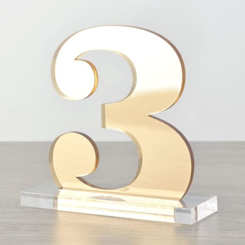 This is a gold table numbers by Em and Me Studio called clarendon table numbers, gold, small in standard