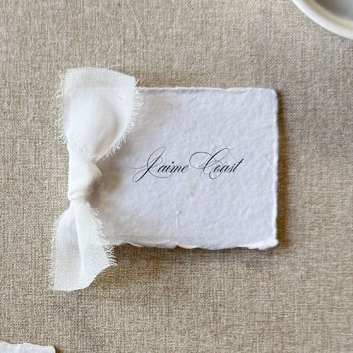This is a white wedding place cards by Cotton and Bow called handmade paper place cards with white bow | set of 10 | custom text in standard