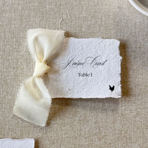 This is a white wedding place cards by Cotton and Bow called handmade paper place cards with ivory bow | set of 10 | custom text in standard