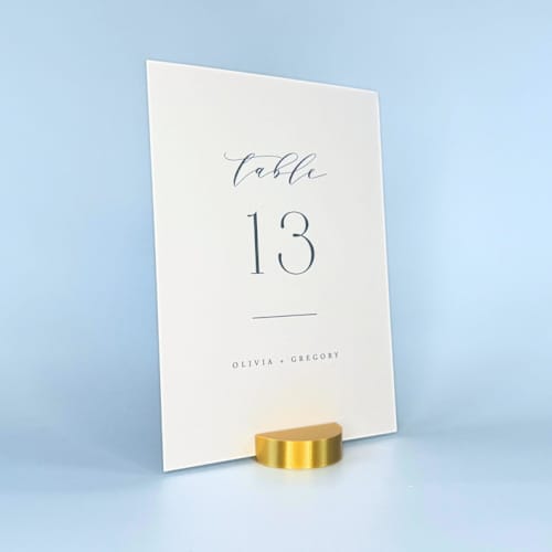 This is a gold place card holders by Corduroy Effect called gold color round table number holder, set of 5 in standard