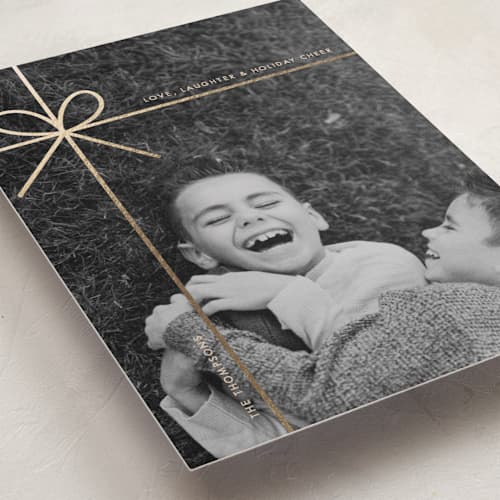 This is a champagne foil pressed holiday cards with foil pressed by Joyce Pinheiro called tied in cheer printing on recycled smooth signature in standard