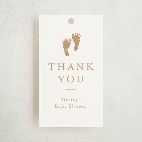 This is a golden baby shower favor tags with standard by Stacey Meacham called footprint printing on signature in tag