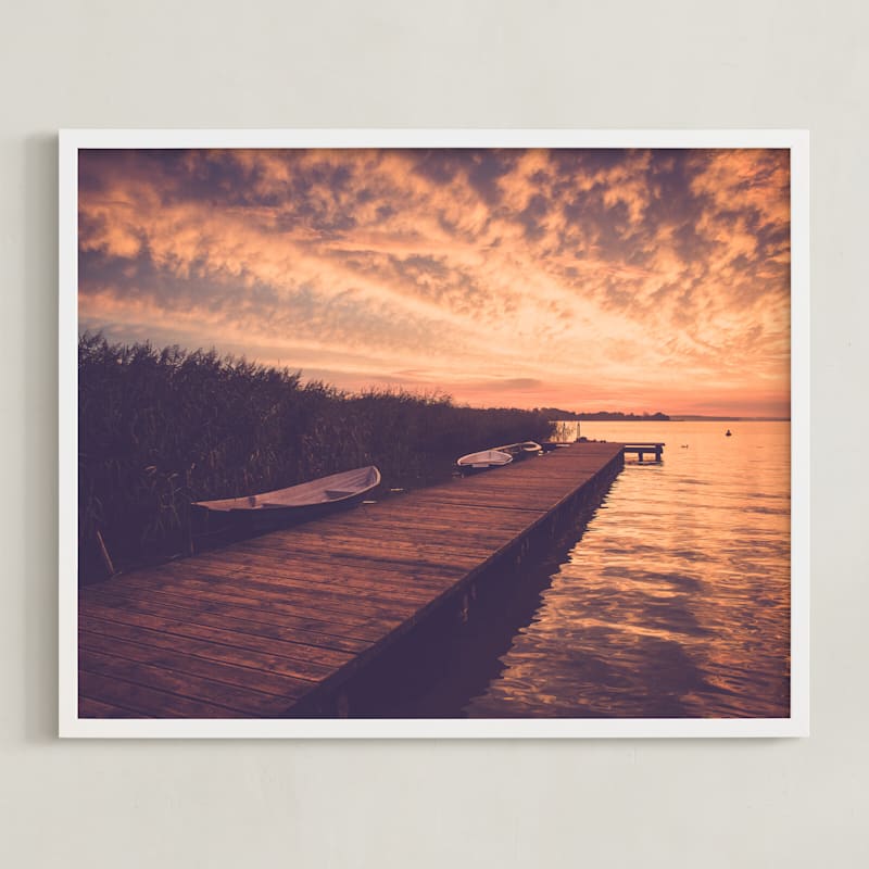 "Red sunset and boat" by Lying on the grass in beautiful frame options and a variety of sizes.